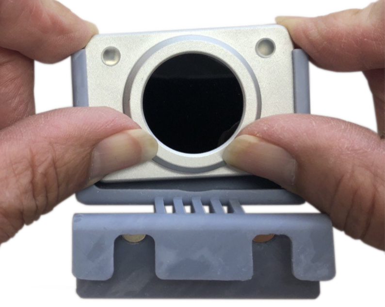 Removing HeadMouse Nano from its 3D Printed mount. Picture illustrating how to release HeadMouse Nano clips and remove it from the 3D printed mount.